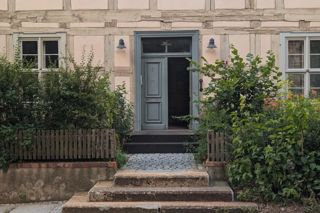 Hauseingang eines Fachwerkhauses mit Steinstufen, Vorgarten und offen stehender Haustür