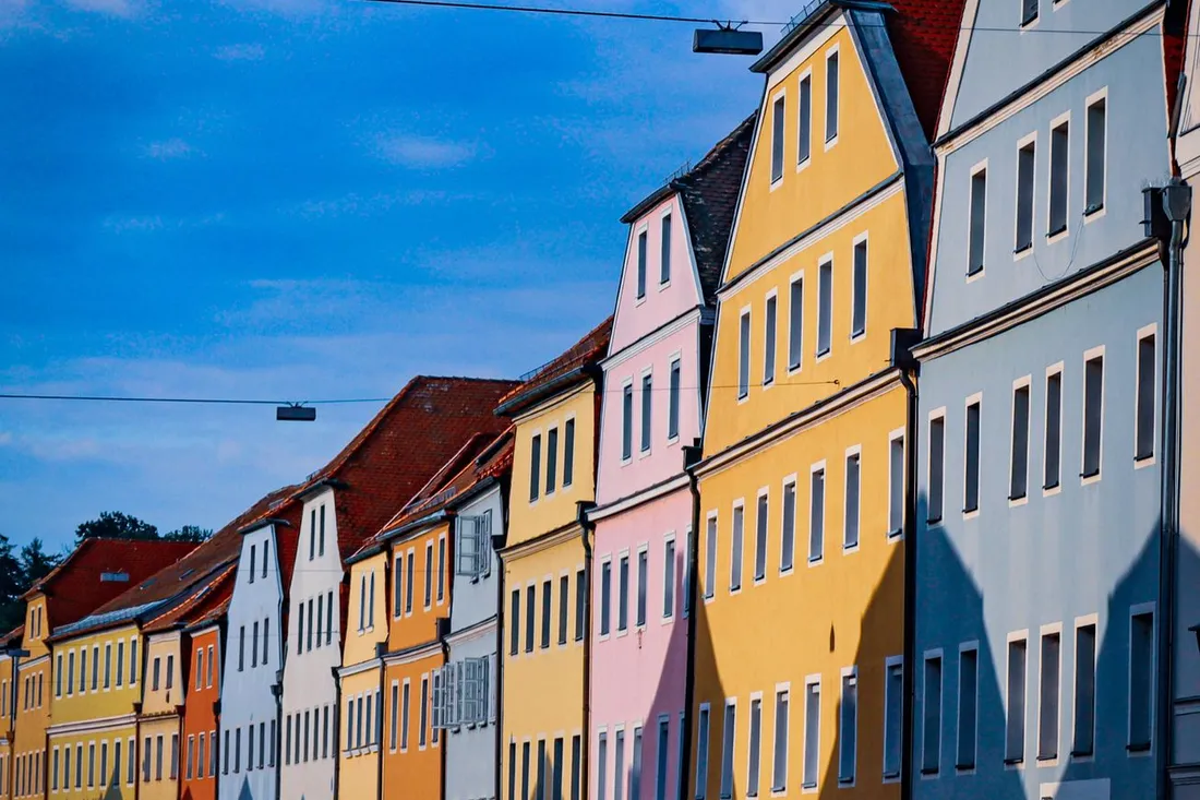 Bunte Giebelhäuser einer historischen Altstadtzeile unter blauem Himmel